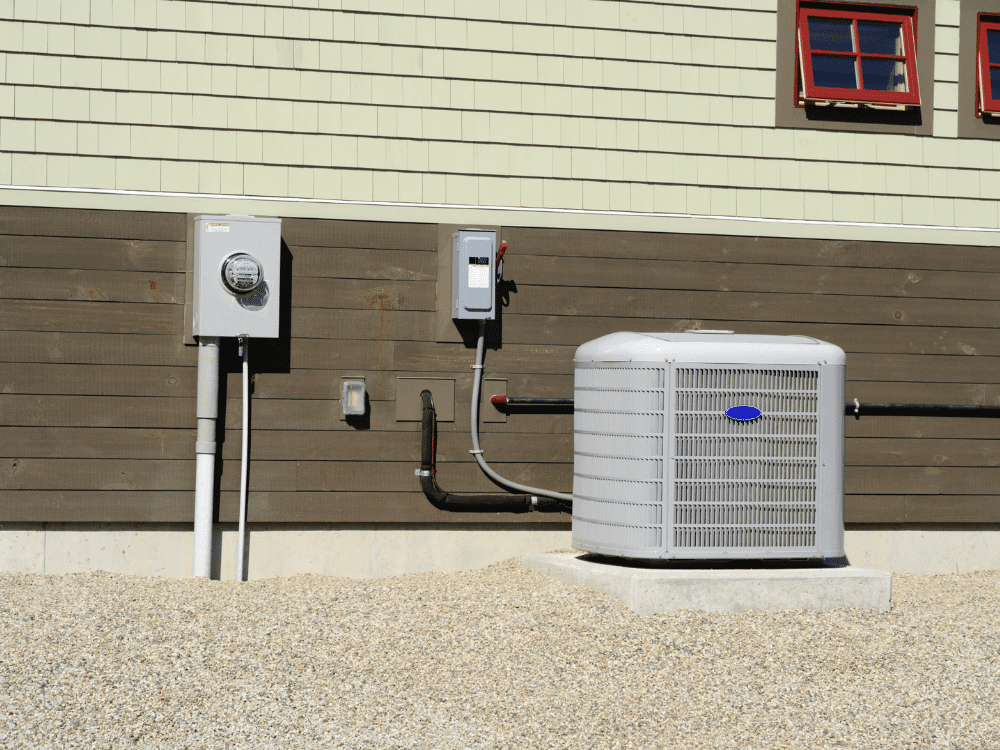 Outdoor air conditioning condenser unit installed beside a home with electrical connections